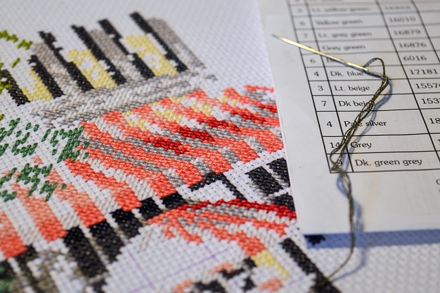 A floss color key list next to a piece of cross-stitch in progress