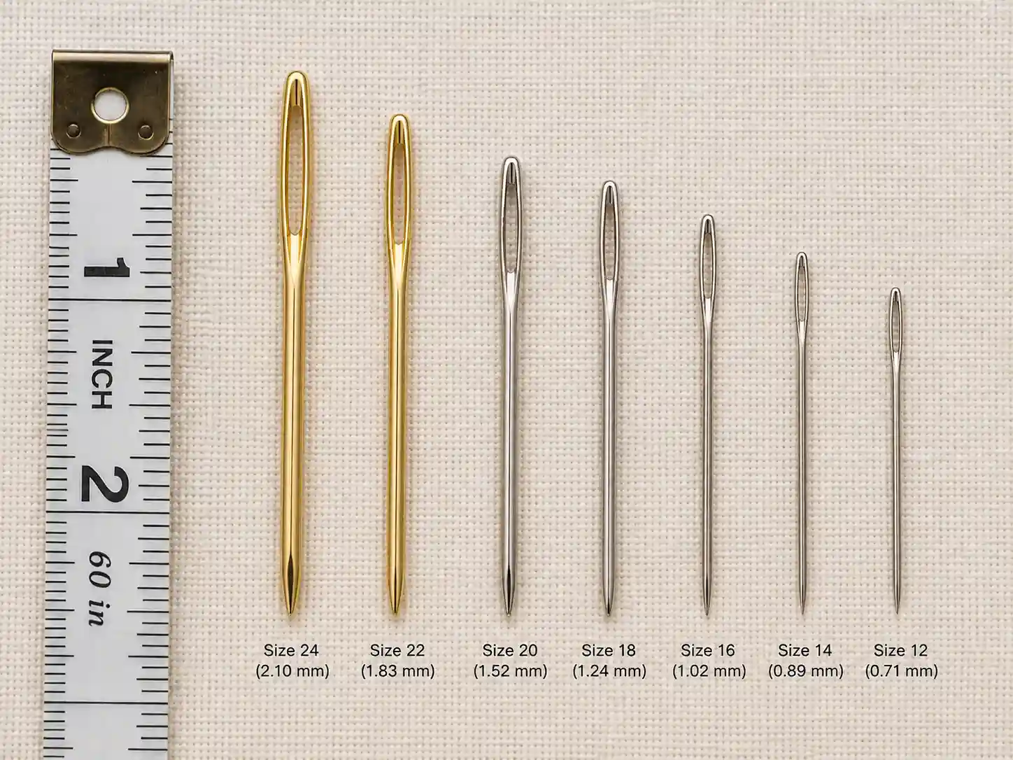 Tapestry needles in sizes 12 through 24 lined up next to a ruler to show their relative lengths