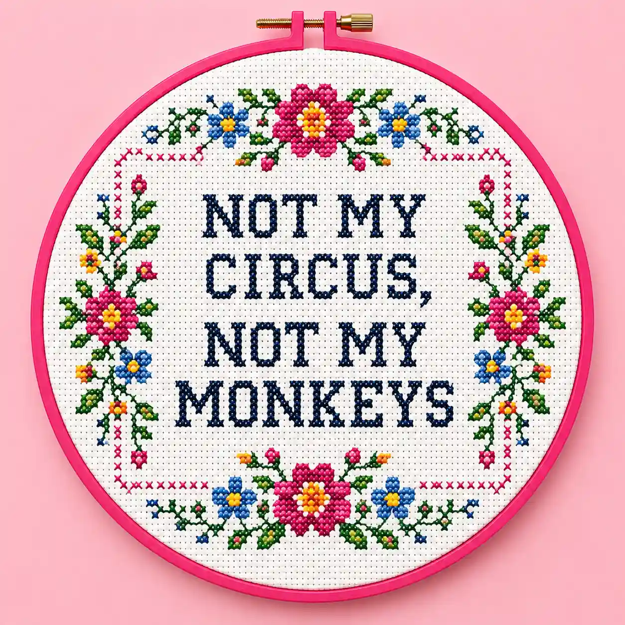 A pink floral-bordered hoop reading "Not My Circus, Not My Monkeys" in bold cross stitch