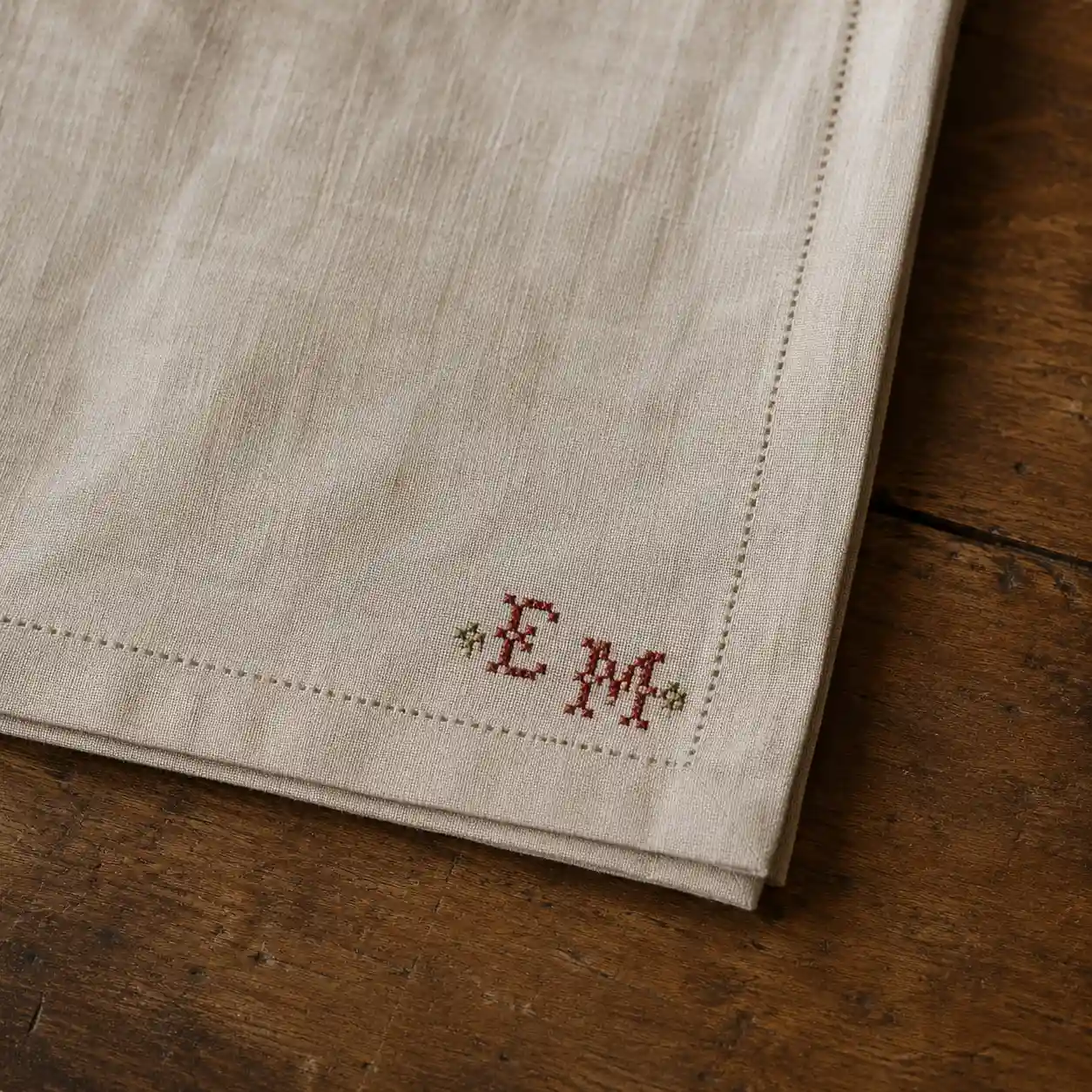 Small stitched initials in the corner of a plain linen napkin
