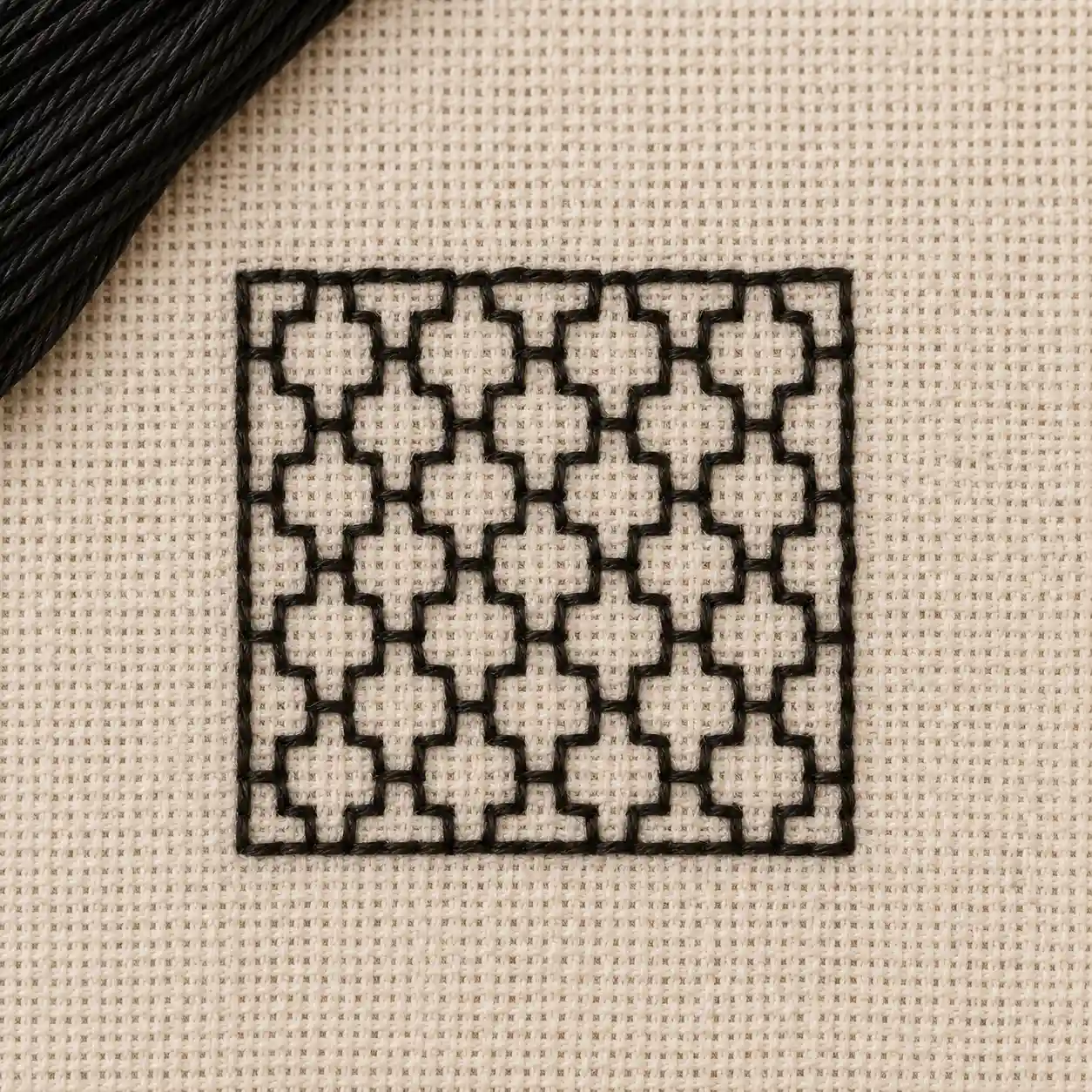 A repeating geometric fill pattern worked in black thread on light linen