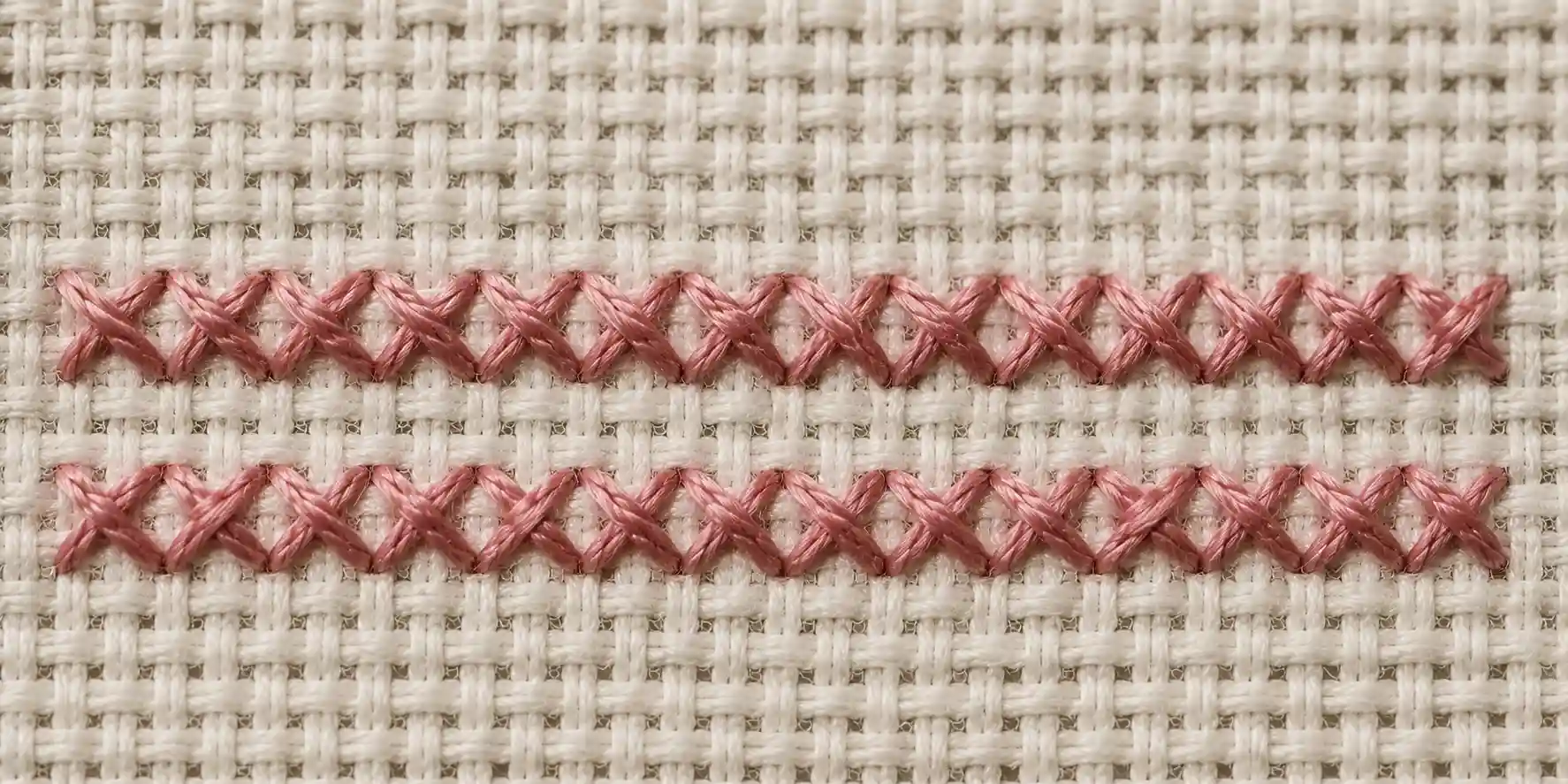 Two rows of cross stitch catching the light at an angle, showing consistent stitch direction